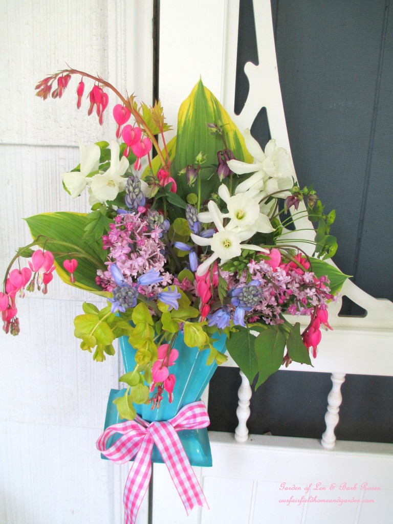 May Day Basket hung on the screen door handle. https://ourfairfieldhomeandgarden.com/diy-project-gather-flowers-for-a-may-day-basket/