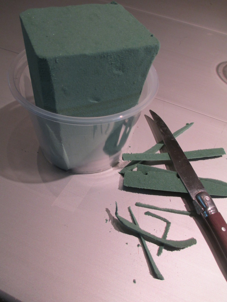 https://ourfairfieldhomeandgarden.com/diy-project-blooming-topiary/Step # 1 ~ trim the oasis so it fits into a small plastic container, then insert in your clay pot